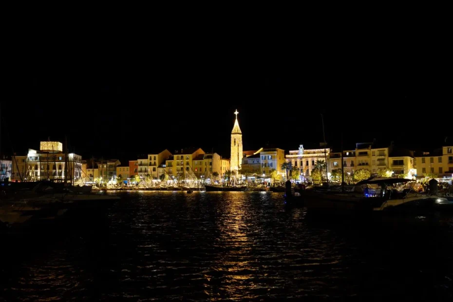 Panoramic night view of Sanary-sur-Mer harbour with Christmas lights and the illuminated church tower.