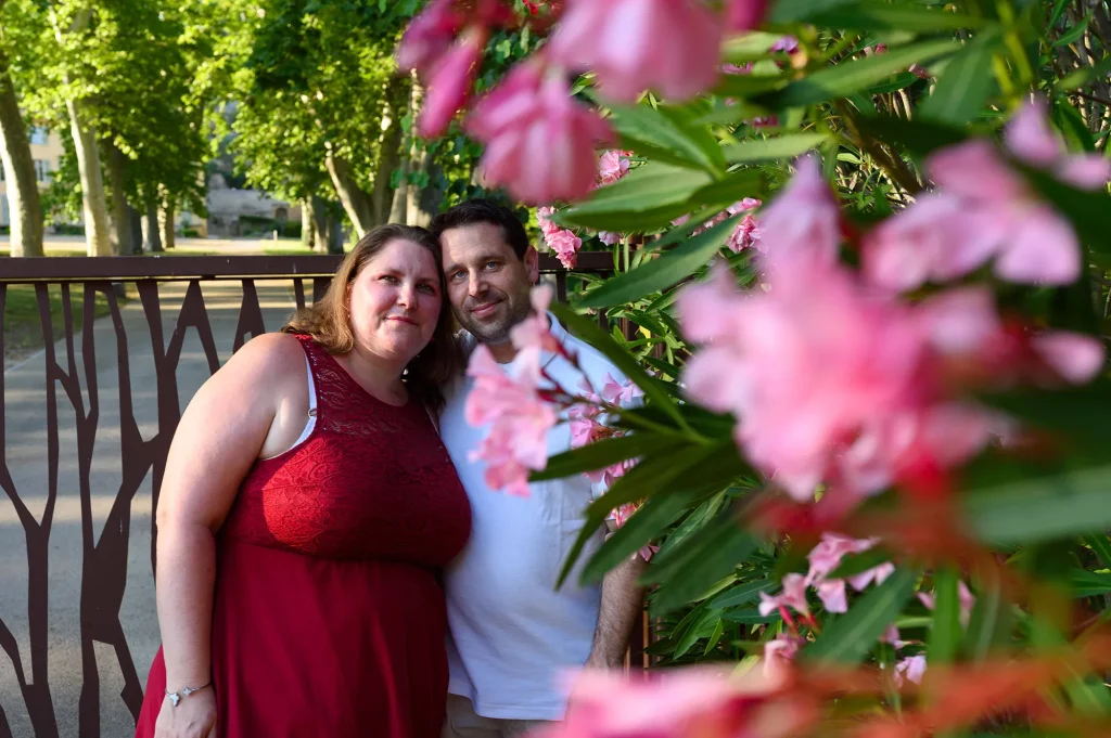Couple photographed during an engagement session in Le Tholonet behind pink flowers