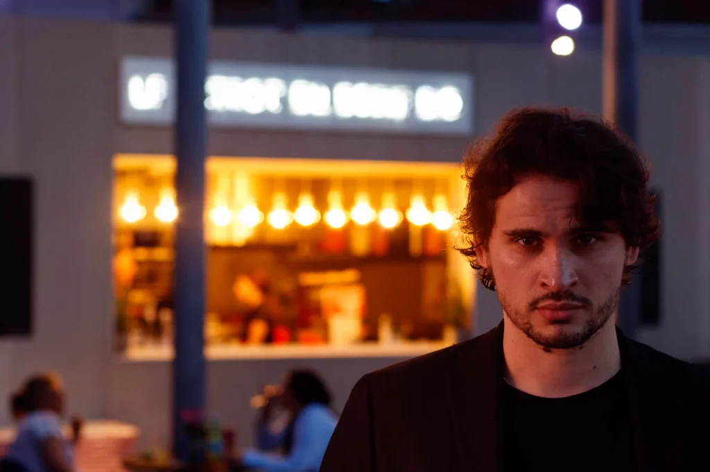 Portrait of a man in a black jacket in front of city lights in the evening