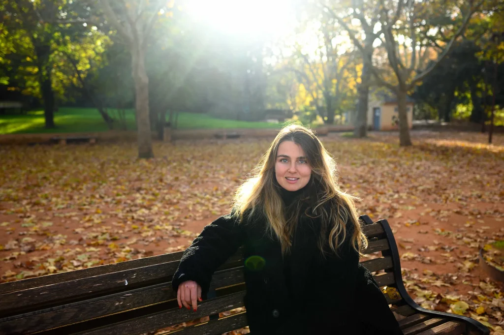 Portrait of a woman sitting on a bench in a park in autumn, in natural light