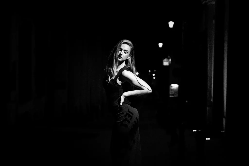 Black and white portrait of a woman in a dark street with dramatic lighting