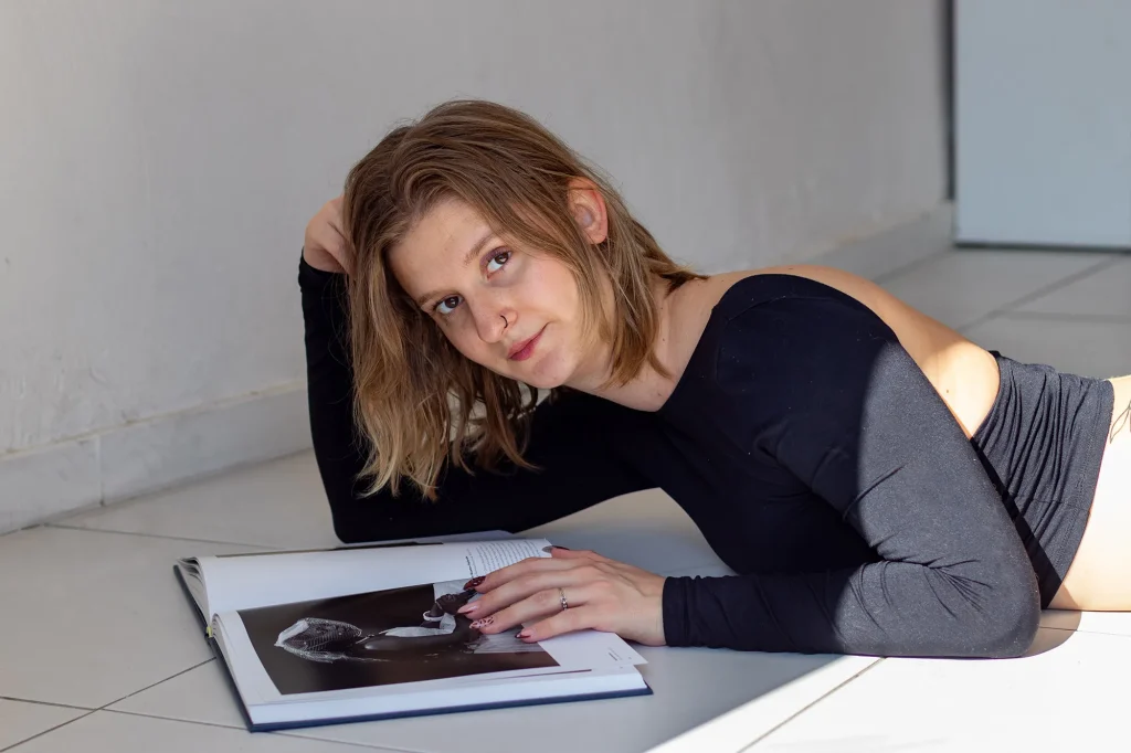 Portrait of a woman lying on the floor with an open book, in natural indoor light