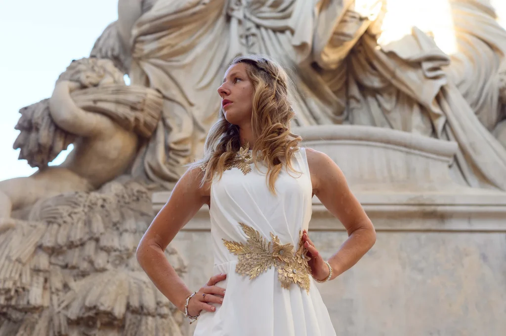 Portrait of a woman in a white dress in front of a stone monument, in an elegant setting in Marseille