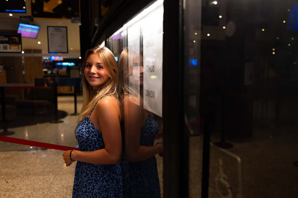 Portrait of a smiling woman at night with a reflection in a window, in an urban setting in Aix-en-Provence