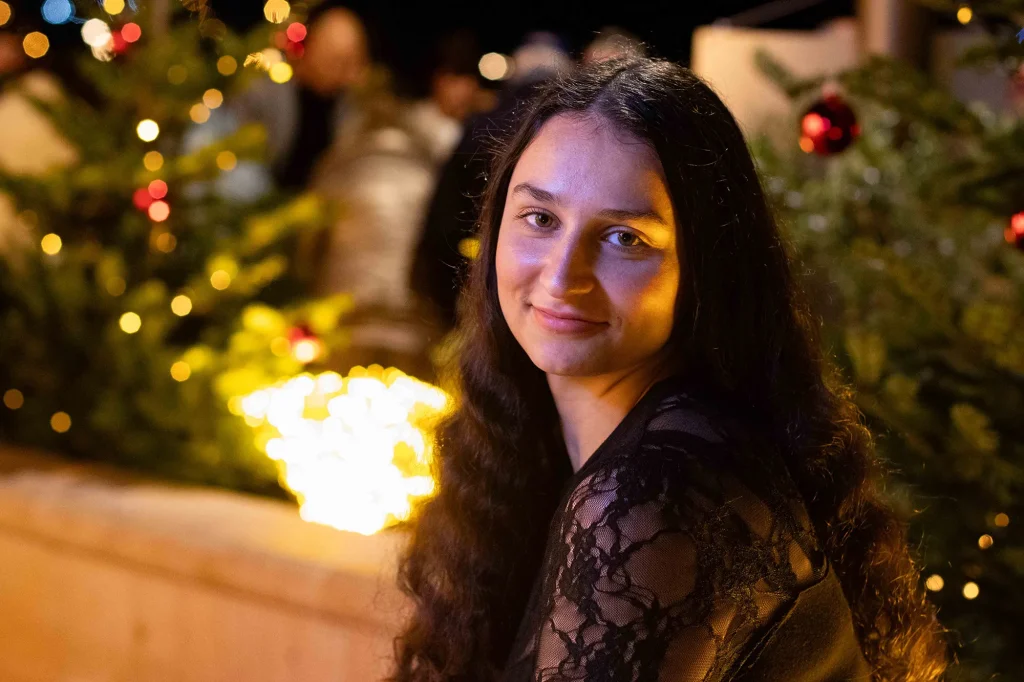 Portrait of a young brunette woman at night with Christmas lights in the background in Sanary