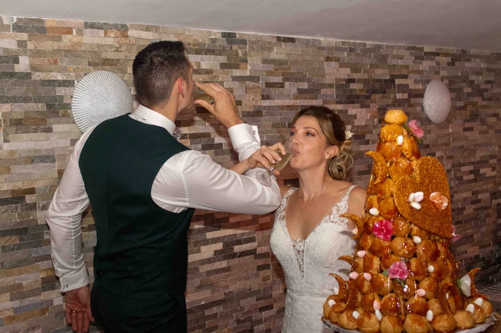 Newlyweds drinking champagne in front of their wedding croquembouche during a reception in Trets