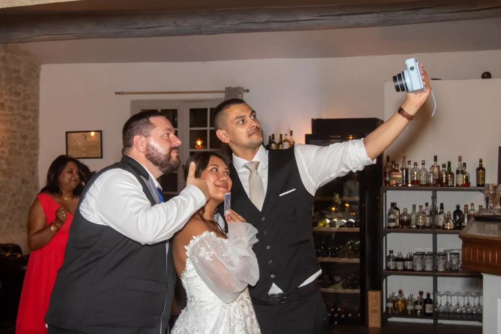 Mariés faisant un selfie avec un invité pendant leur réception de mariage à Miramas-le-Vieux