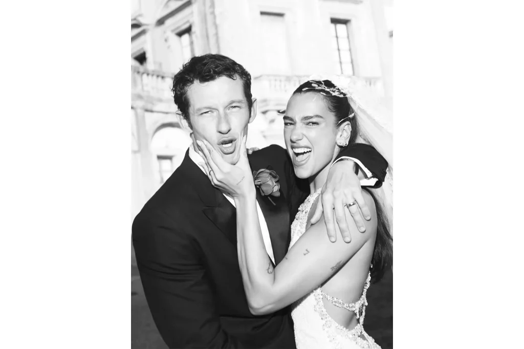 Dua Lipa et Callum Turner en train de rire lors de leur mariage à Palerme, robe de mariée à dos nu et costume noir élégant