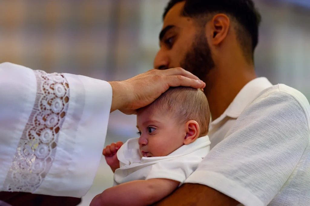 Le prêtre bénit le baptisé pendant la cérémonie religieuse d'un baptême chaldéen à Marseille
