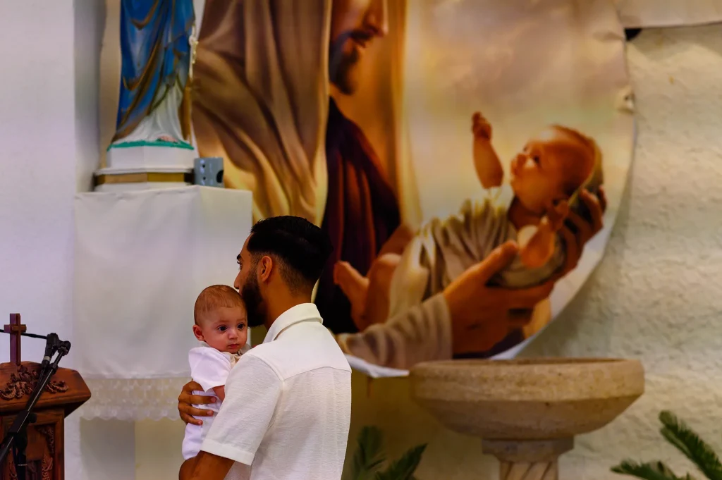 Intérieur sobre de l'église Notre-Dame de Chaldée à Marseille, avec les fonts baptismaux en pierre et une fresque du Christ