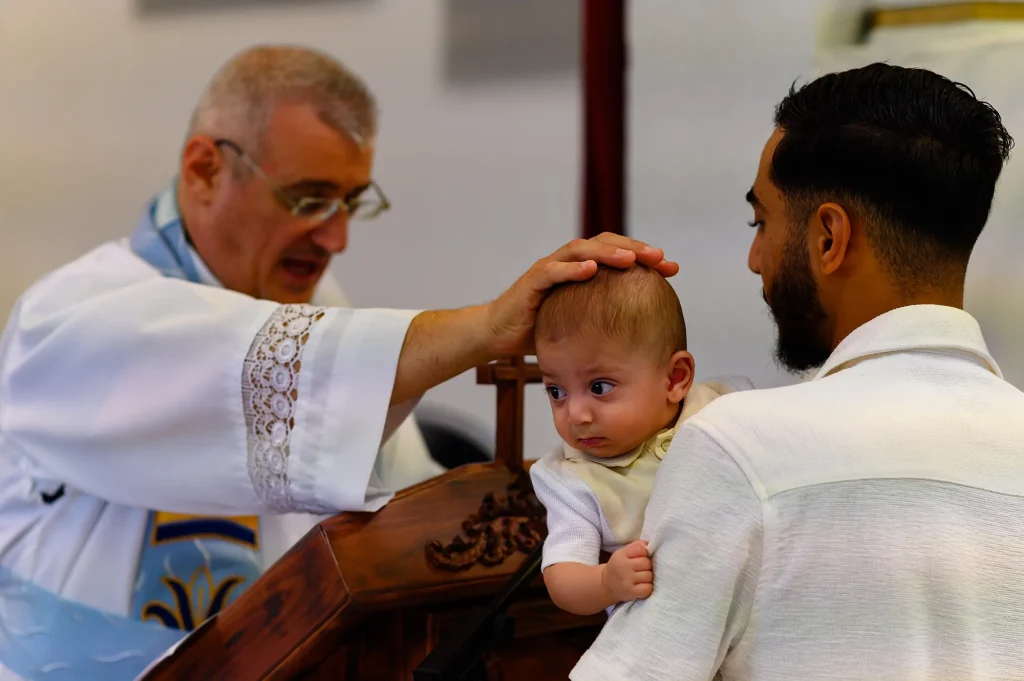 Un prêtre pose la main sur la tête d'un bébé lors d'un baptême de rite chaldéen à Marseille