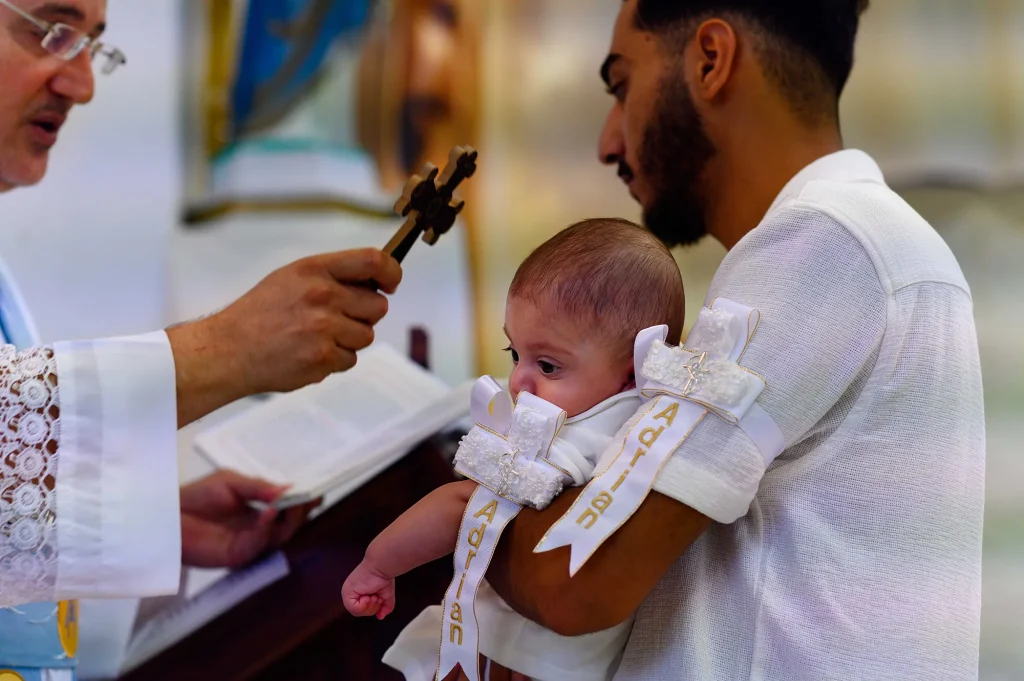 Le parrain tient le baptisé dans sa tenue de cérémonie pendant le baptême à Marseille