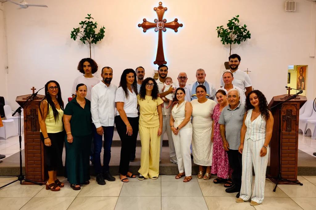 The family gathered around the baby and the priest after the baptism ceremony in Marseille