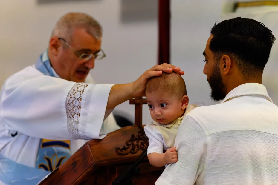 A priest places his hand on a baby's head during a Chaldean-rite baptism in Marseille