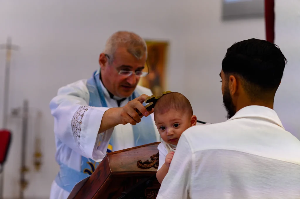 The priest blesses the child with a cross at the start of the Chaldean ceremony in Marseille