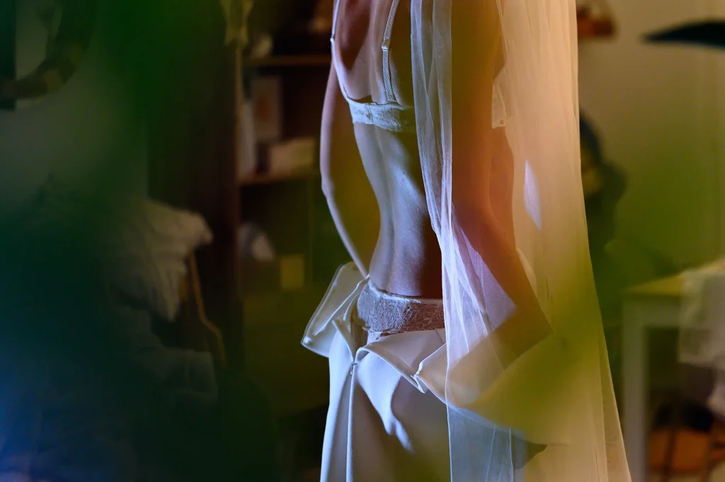 Mariée se dévêtissant en douceur pendant une séance boudoir intime à domicile
